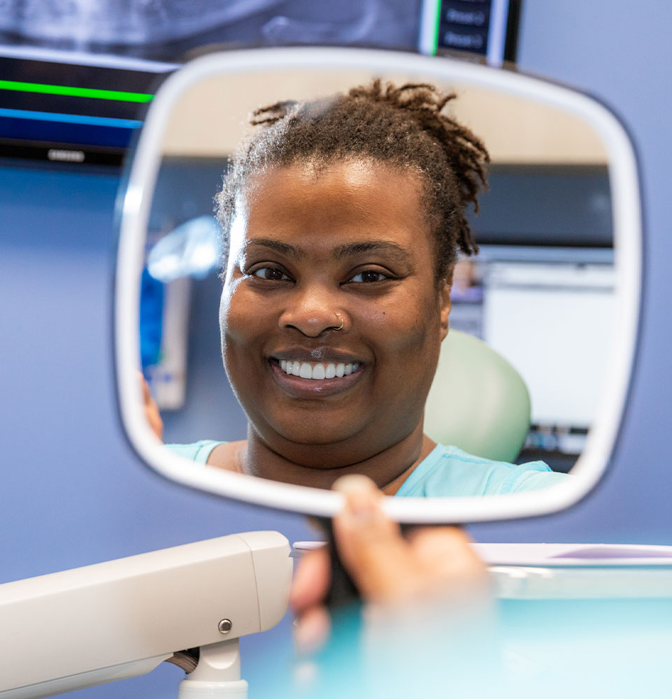 patient smiling in looking in ht mirror after dental procedure